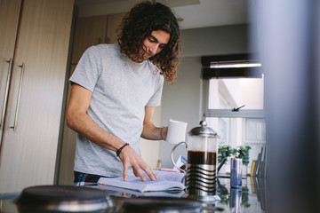 Man reading a book standing in kitchen