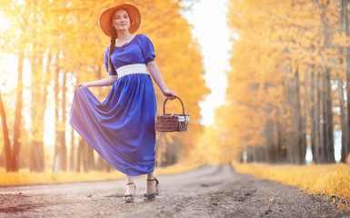Young beautiful girl in dresses on nature. A girl in a hat walks