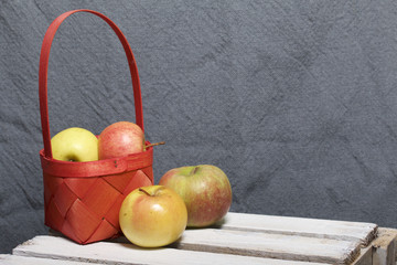 Ripe aromatic apples in a wicker basket. Located on a wooden box, knocked out of the boards.