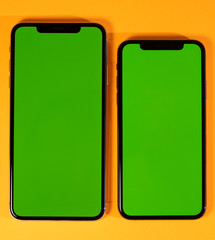 Green chroma key screen on new mobile smartphne hero object on bright glamorous modern neon pop orange background - smartphone ready to insert your app