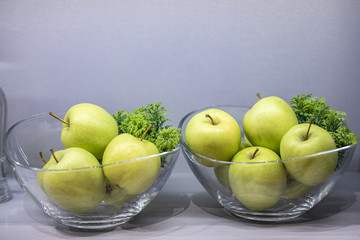 Two galss bowls with fresh green apples on table, closeup