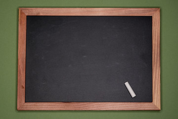 Empty chalk board with wooden frame on green background, blank copy space