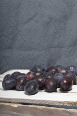 Ripe aromatic plums. Located on a wooden box, knocked out of the boards.