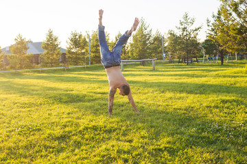 Yoga, fitness and healthy lifestyle concept - man doing a handstand on summer nature