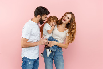 A happy family on pink studio background. The father, mother and son posing together