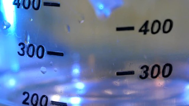 Alcohol fills measuring tank with marks with blue background close-up