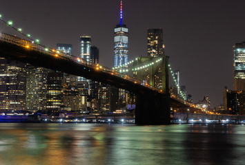 Long time exposure of New York City Manhattan downtown skyline and Brooklyn Bridge  at night viewed...
