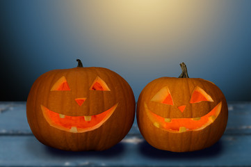 holidays, halloween and decoration concept - close up of carved pumpkins on table over dark blue background