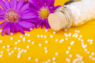 Obraz na płótnie Canvas homeopathic globules on a yellow wooden background