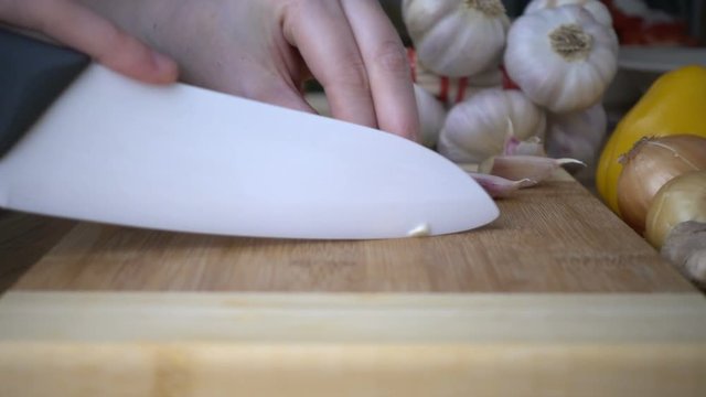 Slicing of garlic on cutting board in slow motion. Cooking concept