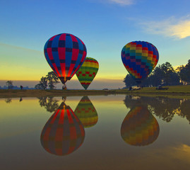 Hot air balloons rising into sky with sunrise