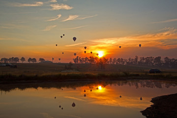 Hot air balloons rising into sky with sunrise