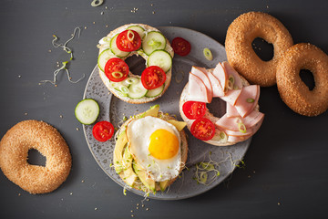 variety of sandwiches on bagels: egg, avocado, ham, tomato, soft cheese, alfalfa sprouts