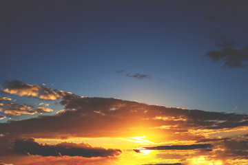view of a warm orange sunset with clouds in dark sky, retro toned
