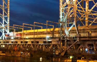 Fototapeta na wymiar Bridge swing night. Boats pass along the river at night.