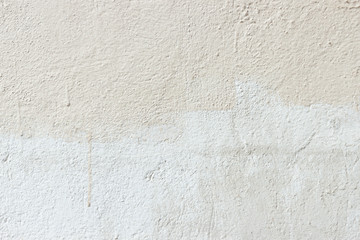 Texture of a wall unevenly painted white and beige