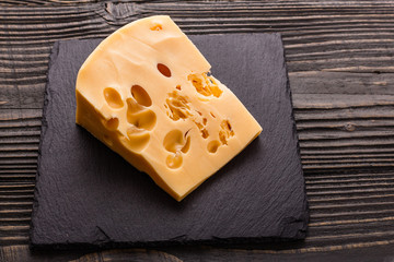 Piece and slices of cheese on a wooden background