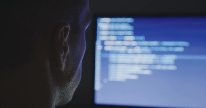 IT Programmer man typing in program code. Developer at work overtime. Hacker hacking late at night.