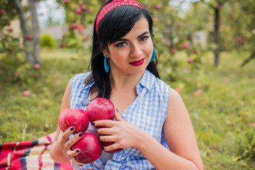 Nice hungry girl with red apple sitting in the park after. Attractive young woman at picnic. Lunch in the park, health food 