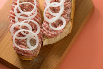 Schweine Mettbrötchen mit Zwiebeln auf Holzbrett