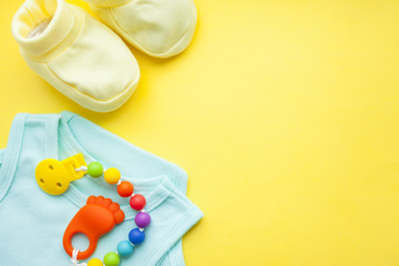 Baby yellow booties. Children's shoes and toys on yellow background. Newborn.