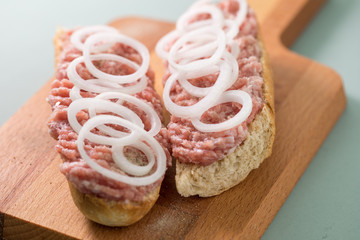 Schweine Mettbrötchen mit Zwiebeln auf Holzbrett
