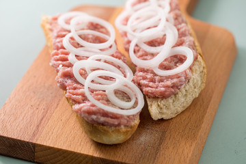Schweinemett Brötchen mit Zwiebeln auf Holzbrett