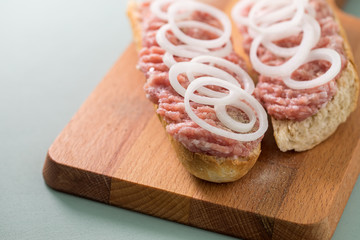Schweine Mettbrötchen mit Zwiebeln auf Holzbrett