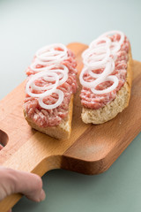 Schweinemett Brötchen mit Zwiebeln auf Holzbrett