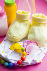 Baby yellow booties. Children's shoes and toys on pink background. Newborn.
