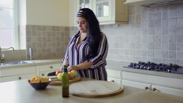 Plump girl is cooking in the kitchen