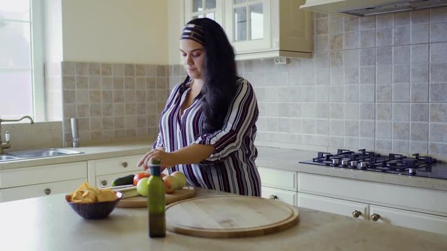 Plump girl is cooking in the kitchen