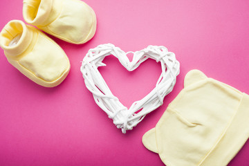 Baby yellow booties. Children's shoes and toys on pink background. Newborn.