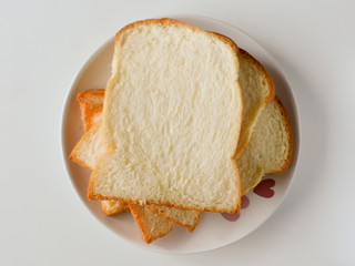 A few slices of toast bread overlay on a white plate for breakfast isolated on white background .Toast is made by wheat,and is healthy and delicious.