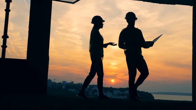 Two constructors are talking while going along the construction site.