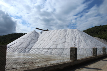 Huge salt mountain in industrial salt mining location with barbed wire and wire fence