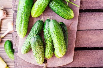 A bunch of fresh cucumbers, dill and garlic on a wooden table. Top view