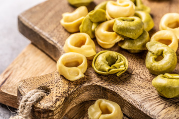 Homemade Tortellini with spinach, cheese and ricotta on wooden board. Gluten free italian food concept.