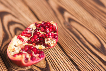 One broken half of red ripe fresh pomegranate on old brown weathered rustic planks