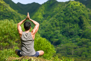 Man doing meditating in a beautiful green nature setting.  - obrazy, fototapety, plakaty