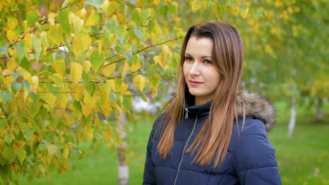 Portrait of happy lovely and beautiful young woman in forest in fall colors. Girl walking in the autumn city Park. 4k