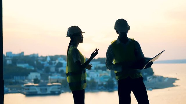 Two inspectors are walking and discussing something while being in a multistory building