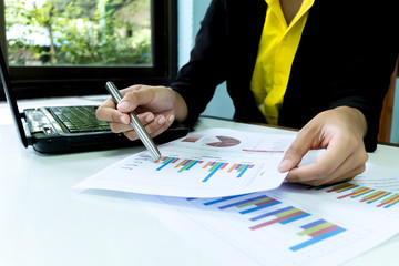 Business women Close-up hand with paper writing at graph, Using Computer Notebook laptop and smartphone, Marketing business for success Concept.