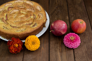 Pie, apples and flowers on a wooden background.