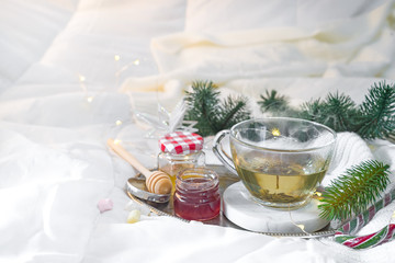 tray with honey and a cup of hot tea in the bed, lazy morning, warm winter mood