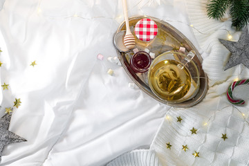 tray with honey and a cup of hot tea in the bed, lazy morning, warm winter mood, flat lay
