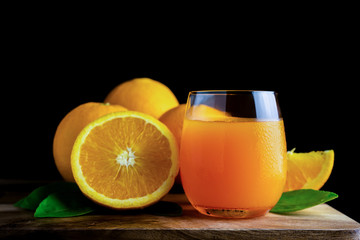 Glass of orange juice with fresh fruits on wooden floor