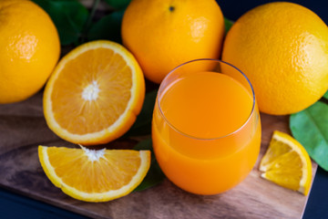 Glass of orange juice with fresh fruits on wooden floor