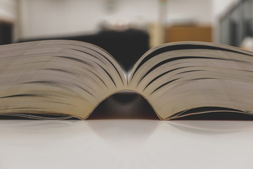 Open book on table and blurred bookshelf. Education background.