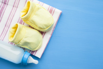 Baby yellow booties. Children's shoes and toys on blue background. Newborn.